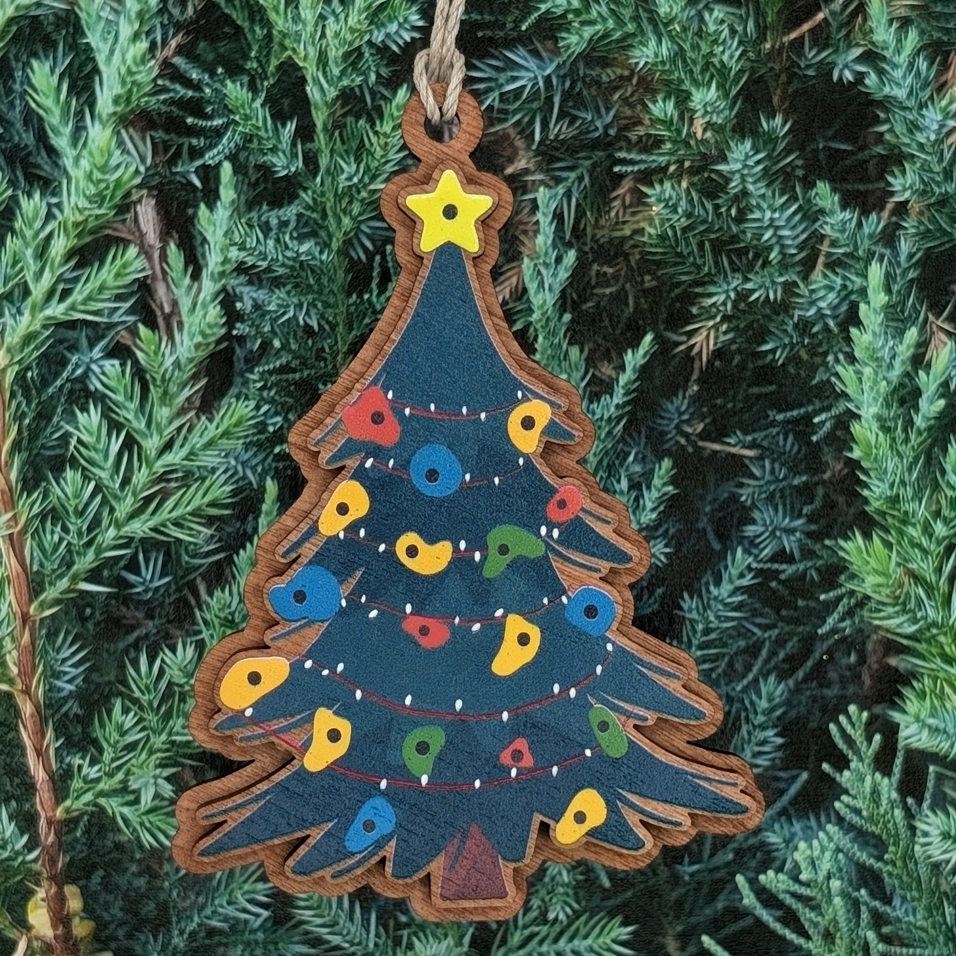 Decorative Christmas tree ornament with colorful rock climbing holds on a green pine branch background